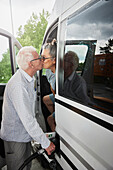 Senior couple refueling van and kissing