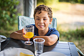 Lächelnder Junge mit Saft in der Hand und Blick in die Kamera