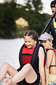 Siblings paddle boarding on lake