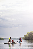 Mother and children paddle boarding