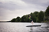 Junge springt vom Paddelbrett auf See