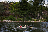 Siblings floating on back in lake