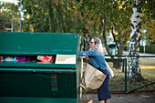 Blonde Frau wirft Müll in den Abfalleimer