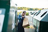 Blonde Frau wirft Müll in den Abfalleimer