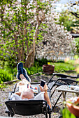 Mann entspannt sich im Garten und benutzt sein Smartphone