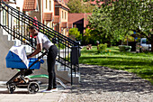 Woman with baby stroller in front of house