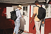 Junge Männer stehen vor einem Holzhaus