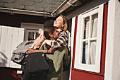 Smiling friends hugging in front of wooden house