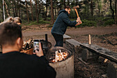 Mann fotografiert einen Freund beim Holzhacken