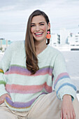 Young woman wearing a light knitted jumper with colorful stripes