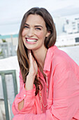 Young woman in salmon coloured shirt with pearl necklace