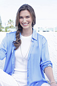 Junge Frau in weißem T-Shirt, blauer Longbluse und weißer Hose