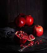 Whole and broken pomegranates against a black background