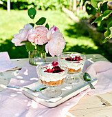 Käsekuchen mit Beerenkompott serviert in Dessertschalen auf Tisch im sommerlichen Garten