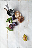 Fresh plums and shiitake on a white wooden background