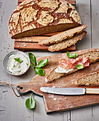 Homemade rustic crusty bread with herb spread and salami
