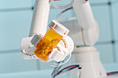 Robotic arm holding bottle of tablets