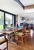 Rustic wooden dining table with matching chairs in front of floor to ceiling windows