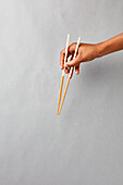 Hand holding chopsticks down
