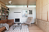 Modernes Wohnzimmer mit hellen Holzelementen, Kamin und Leder-Sitzmöbeln
