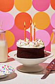 Chocolate birthday cake with vanilla icing and three orange candles