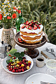 Gedeckter Tisch mit Kuchen, Blumenstrauß und Beeren im Freien