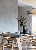 Long dining table with classic chairs in front of a concrete wall
