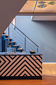 Kitchen with black and white zig-zag pattern in front of staircase
