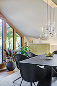 Elegant dining room with dark shell chairs, above a pendant light with glass globes