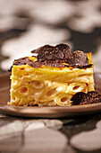 Slice of baked macaroni topped with truffle slices