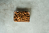 Organic almond nuts in the bowl on concrete background