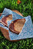 Slices of chocolate frosted cake wrapped in napkins on the grass