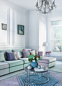 Weißes Wohnzimmer mit zweifarbigem Sofa, Kissen und Couchtisch mit Blumenarrangement
