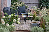 Sitzplatz mit Tisch, Stühlen und Miniteich auf sommerlicher Kies-Terrasse