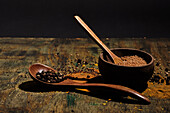 Pepper and coriander with wooden bowl and wooden spoon with spices on wood