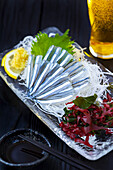 Sashimi vom Silberstreifen-Rundhering, serviert mit Bier