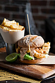 Burger with fried fish served with wavy cut fries