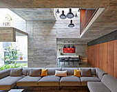 Open living room with sofa set and view to dining room in a concrete house