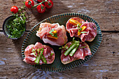 Canapes with ham, salami, asparagus and tomatoes on a platter