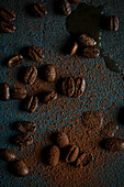 Kaffeebohnen mit Kaffeepulver auf dunklem Untergrund