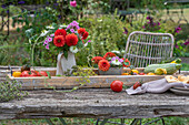 Dahlia bouquet and freshly harvested garden vegetables on wooden tray