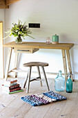 Kleiner, gewebter Teppich, Schreibtisch mit Holzhocker, Bücherstapel, Soda- und Ballonflaschen