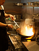 Cook with wok in a restaurant kitchen