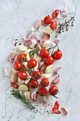 Peeled garlic, cherry tomatoes, and garlic peel on a marble table