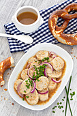 White sausage salad with onions, mustard dressing and pretzels