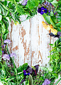 Fresh herbs and flowers creating a picture border with copy space