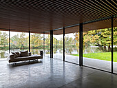 Minimalist living room with all-round glazing and lake view