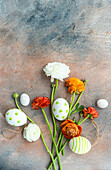 Decorative Easter eggs and ranunculus on concrete background