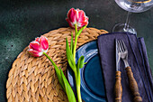Gedeck mit Korbuntersetzer, blauem Keramikteller und Tulpen (Tulipa)