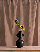 Sonnenblumen in einer Vase vor kariertem Vorhang